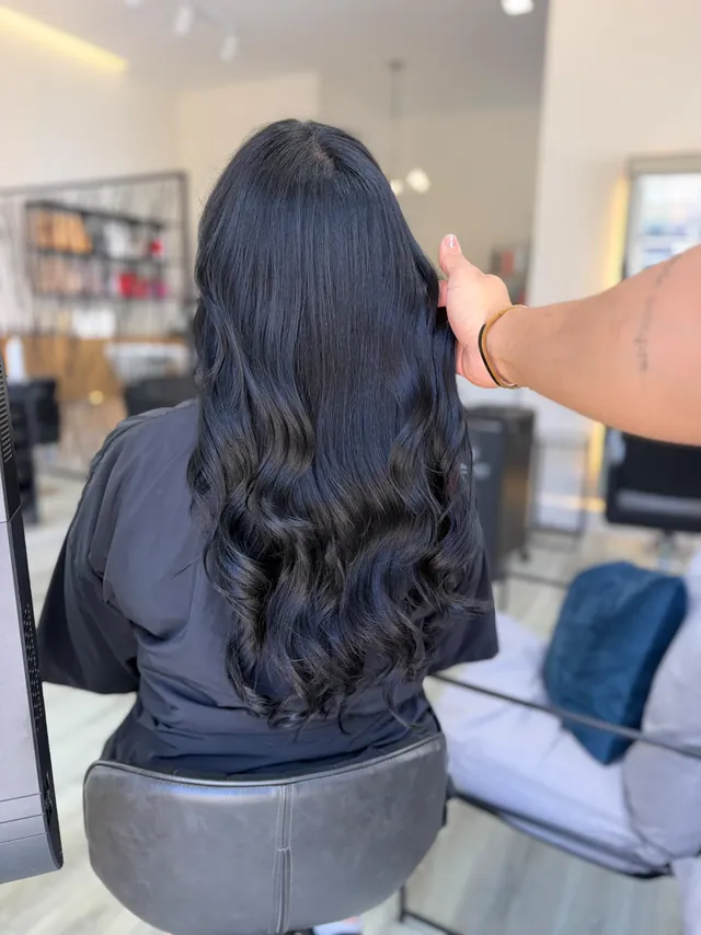 Extensões de luxo em castanho muito escuro, com volume e ondas, vistas de costas no salão